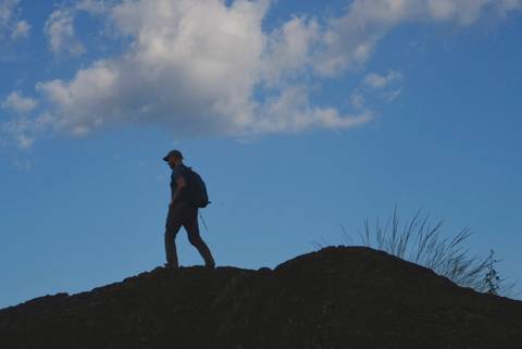       Silhouette of a hiker on a ridge against a blue sky.
  