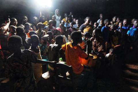       Group of people gathered in a dimly lit room engaged in an activity.
  
