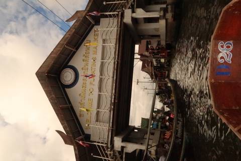       Floating market entrance with flags and visitors.
  