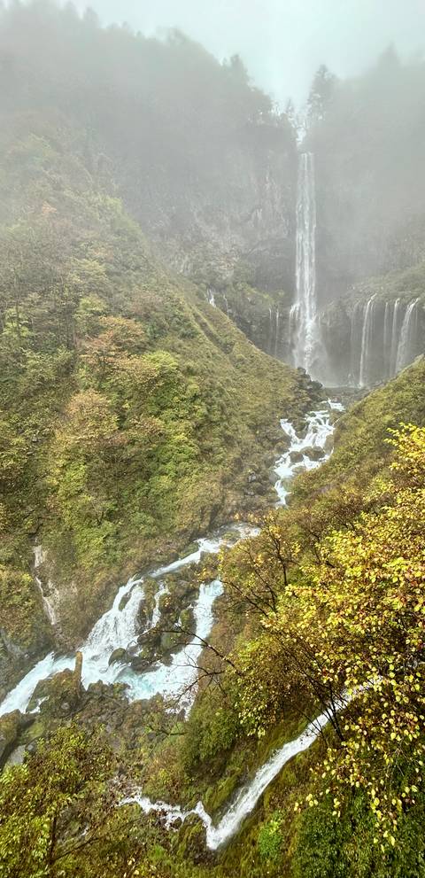       Waterfall cascading down a rocky hillside surrounded by green foliage.
  