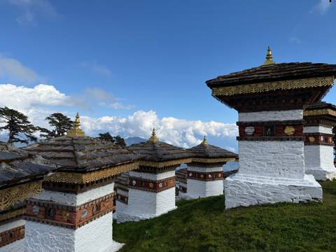       A row of white stupas with intricate decorations under a cloudy sky.
  