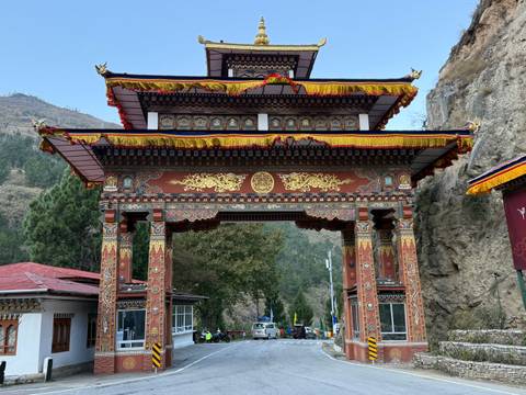      An ornate gateway with colorful decorations and cloudy skies.
  