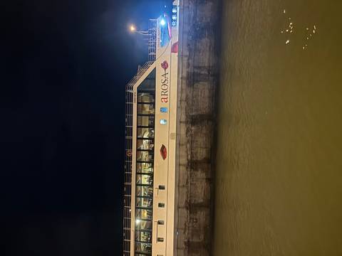 Cruise ship docked at night with lit windows.