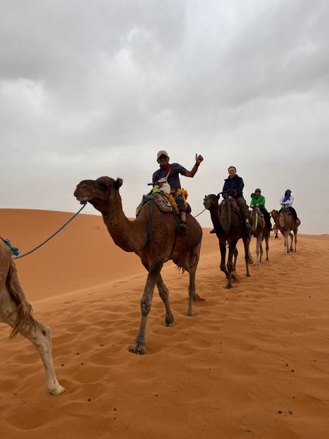 People riding camels in a desert landscape.