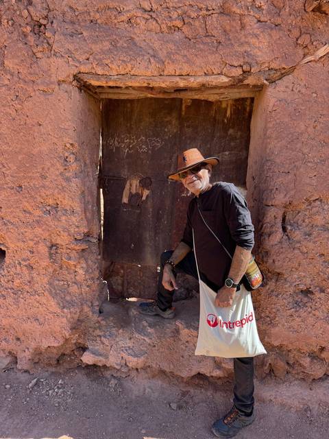 Man posing against a rustic wall.