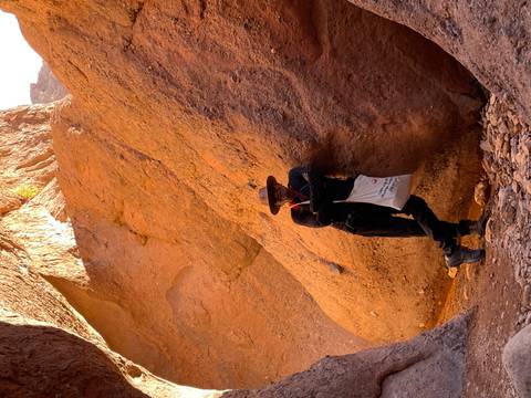       Man leaning against large rock formations.
  