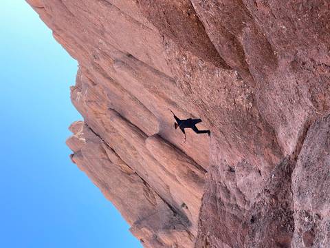       Person climbing rocks in a desert landscape.
  