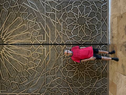 Man standing in front of intricate patterned wall.