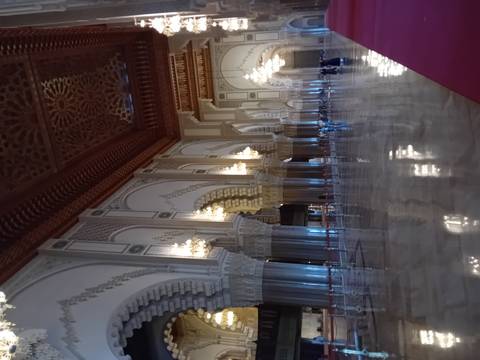      Interior of a mosque with chandeliers and arches.
  