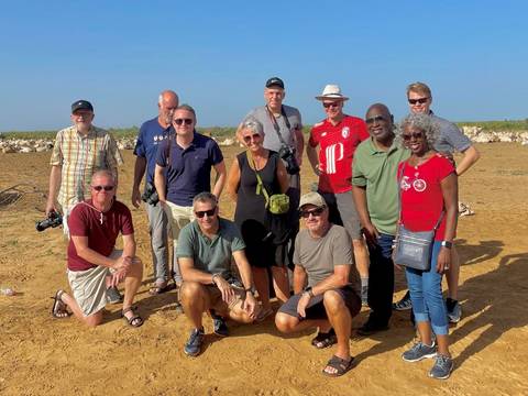 Group photo of several people standing on sandy terrain.