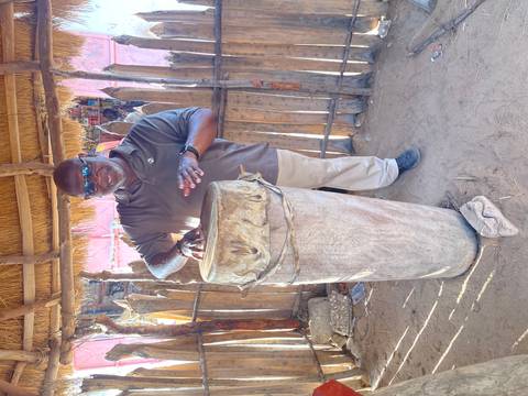 Man playing a large traditional drum made of wood.