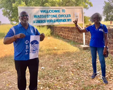 Two people in front of a sign for the Wassu Stone Circles UNESCO site.