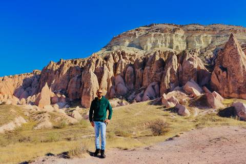 Person standing in front of Cappadocia rock formations.