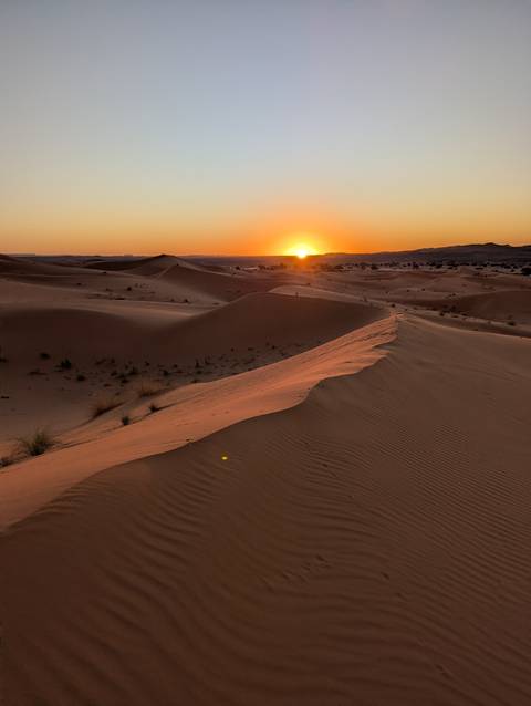 Desert landscape at sunset with sand dunes.