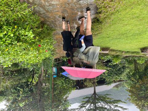       People walking with umbrellas in a garden pathway.
  