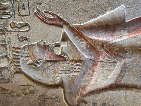Ancient Egyptian relief of a pharaoh or deity painted on a wall.