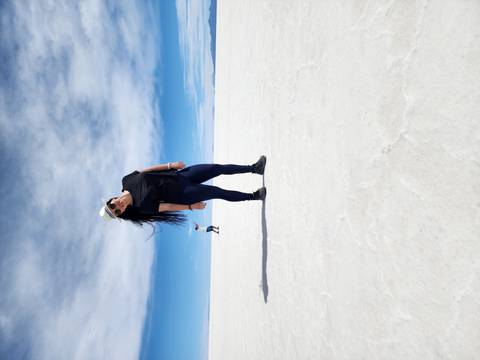       Woman posing on the Uyuni Salt Flats with another person in the distance.
  