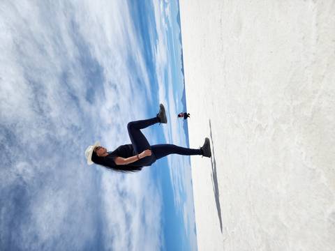 Woman posing creatively on the Uyuni Salt Flats appearing to step on another person.