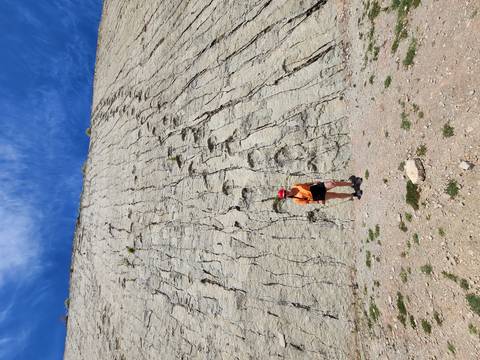 Person standing against a large textured wall resembling rock or salt flats.