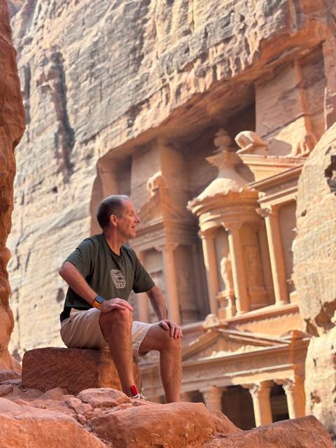 Man sitting in front of the iconic Petra Treasury.