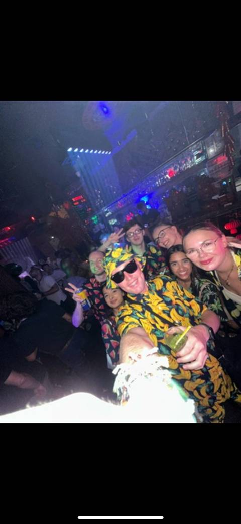 Group of people smiling in a club with vibrant lighting