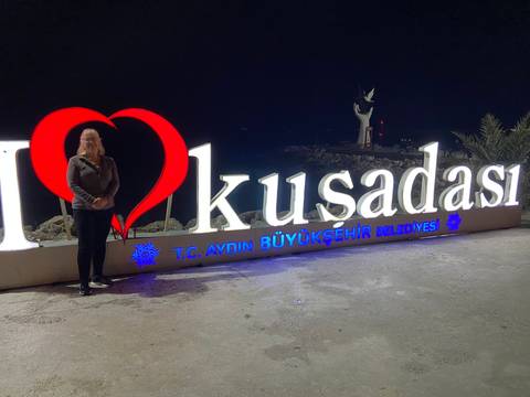       Person standing in front of an illuminated sign at night.
  