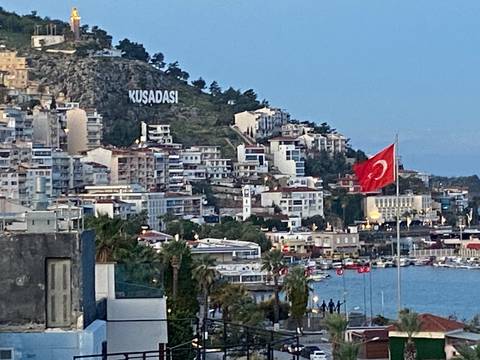       Town on hillside with buildings and Turkish flag.
  