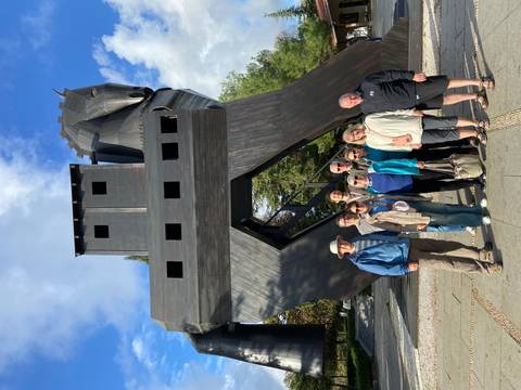       A group of people standing in front of a large wooden horse structure.
  