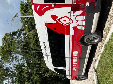 White van parked in a forest area with 'Lupita Overland' branding.