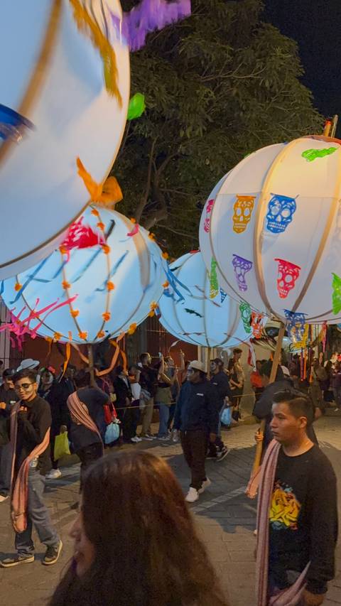 Outdoor event with decorated lanterns and people gathered.