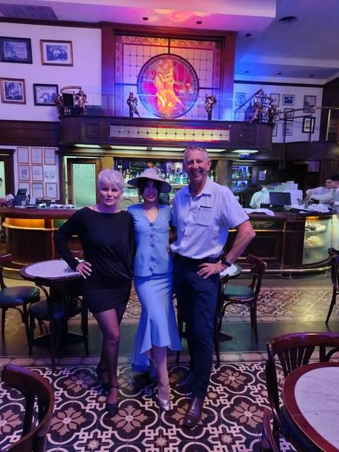       Three people posing inside a bar.
  
