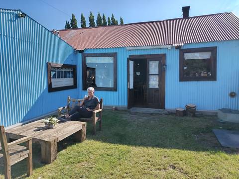       Person sitting outside a blue corrugated building.
  