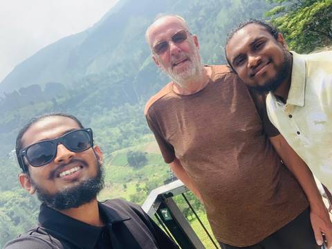 Three men posing for a photo with a scenic mountain background.