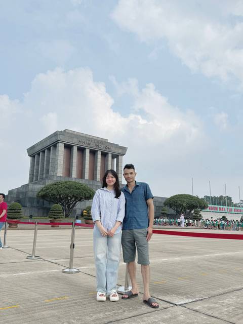       Two people standing in front of a large stone monument.
  