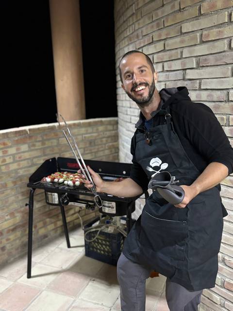 Person grilling food outdoors at night.