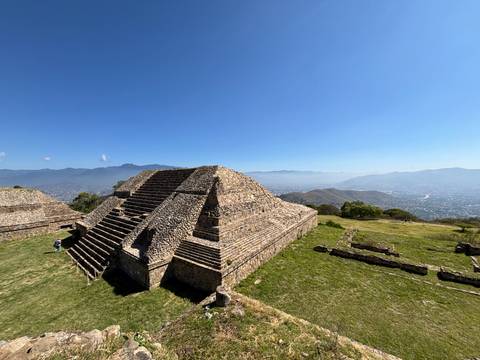 Ancient stone pyramid in Oaxaca with mountains in the background.