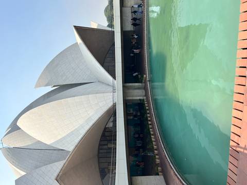       Iconic lotus-shaped building with a pool in front under a clear sky.
  