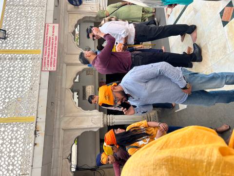       Group of people with headwear in a courtyard area with decorative arches.
  
