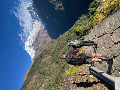 Hikers walking on a mountain trail with a snowy peak in the distance.