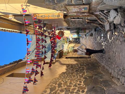 Person standing in a colorful street in Cusco decorated with flags.