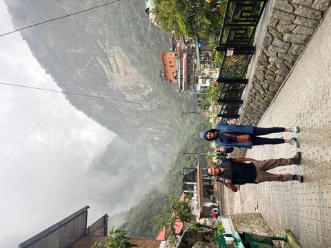 Two people posing on a cloudy day with mountains in the background.