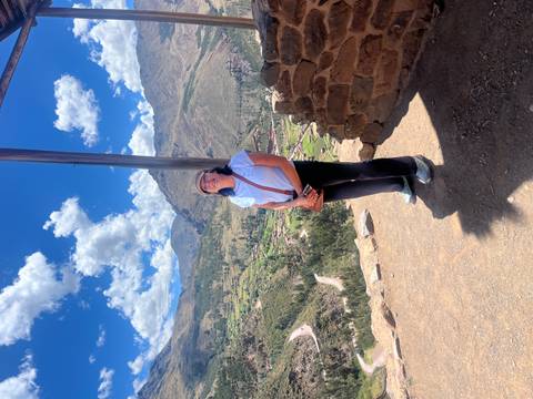 Person posing with a valley and mountains in the background.