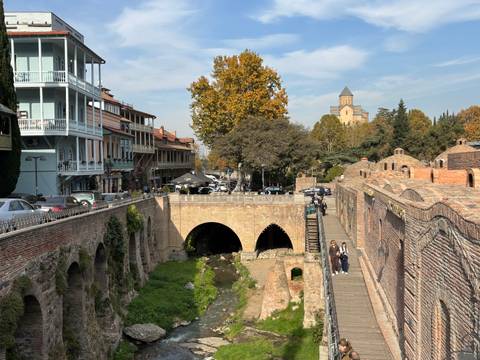 Bridge over a river with historic buildings and trees.