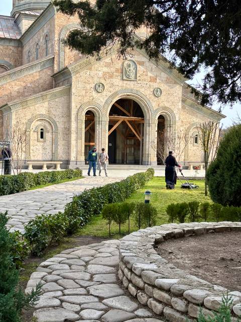 People on a paved walkway by a historic building.
