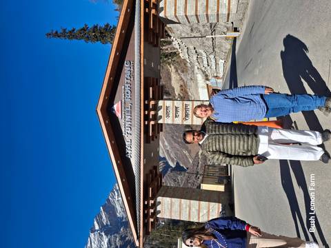 Two people standing at the entrance of the Atal Tunnel with mountains in the background.