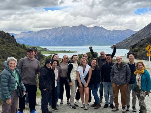 Group of people posing with a scenic mountain and lake background.