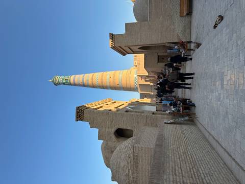       A street view with a tall decorated minaret in Khiva.
  