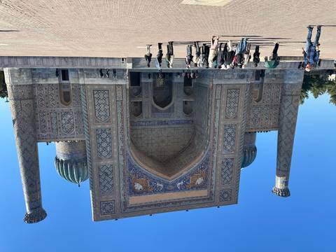       A grand entrance with blue domes and tourists exploring.
  