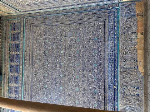       Intricate tilework with patterns, possibly on a historical building wall.
  