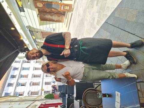 Person taking a photo with a waiter outside a cafe.